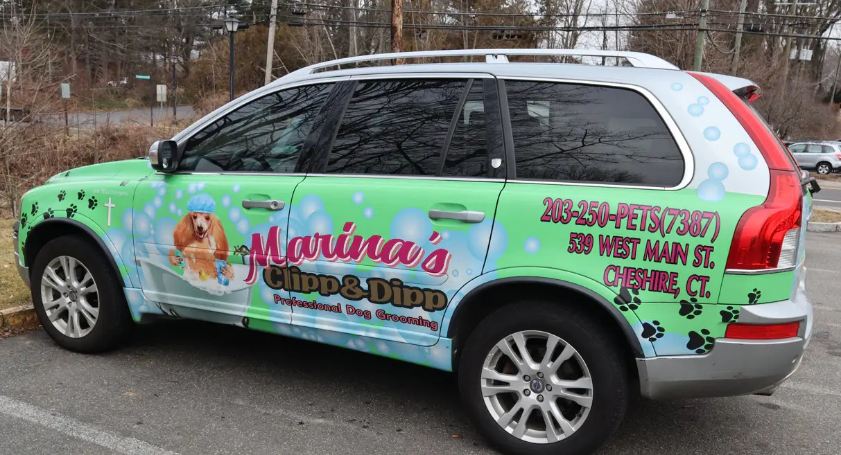 The Marina's Clipp & Dipp salon SUV in a green paw-print wrap reading "Professional Dog Grooming, 203-250-PETS (7387), 539 West Main St., Cheshire, CT"